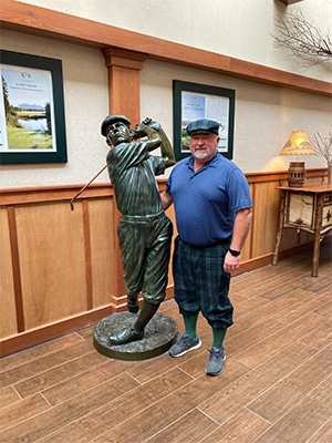 Terrence Croad standing next to a statute swinging a golf club